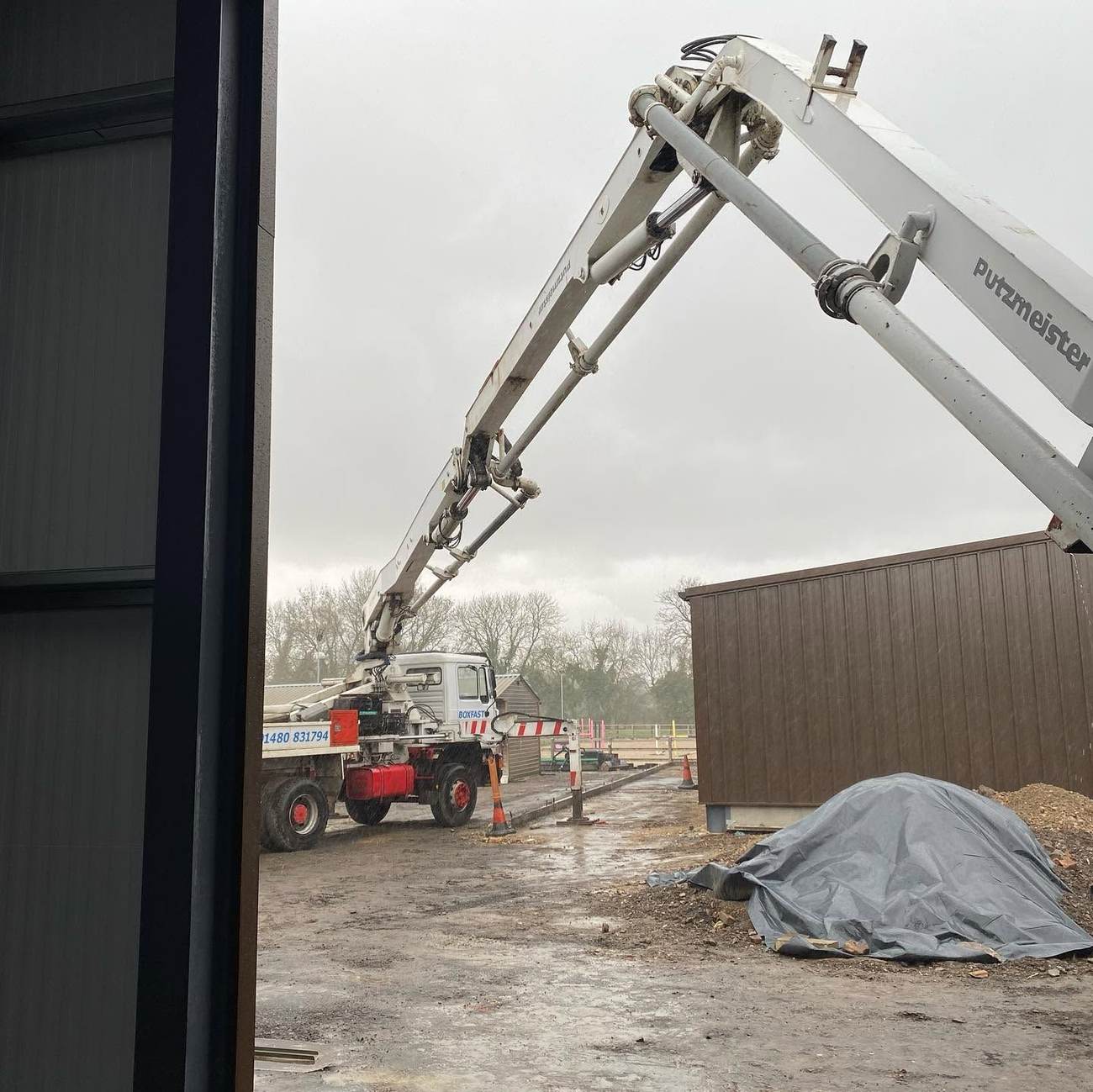 Concrete pump truck placing a slab inside a steel-frame building