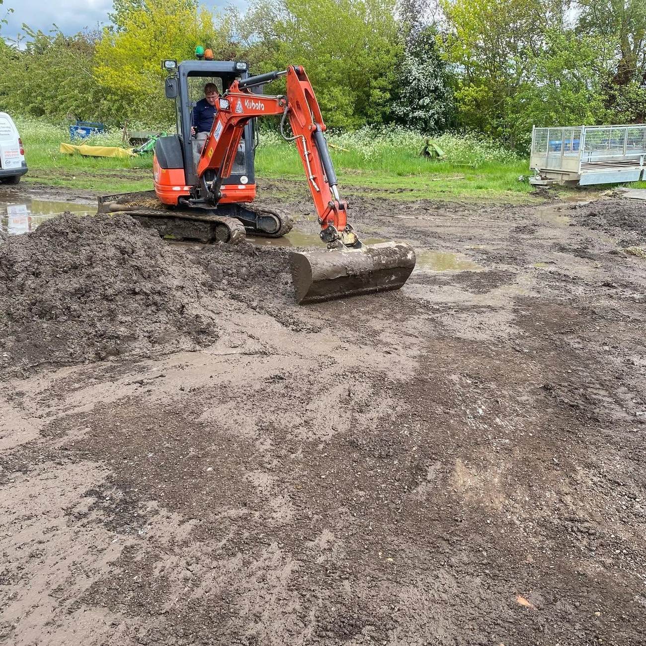Mini excavator carrying out groundworks beside a new-build house