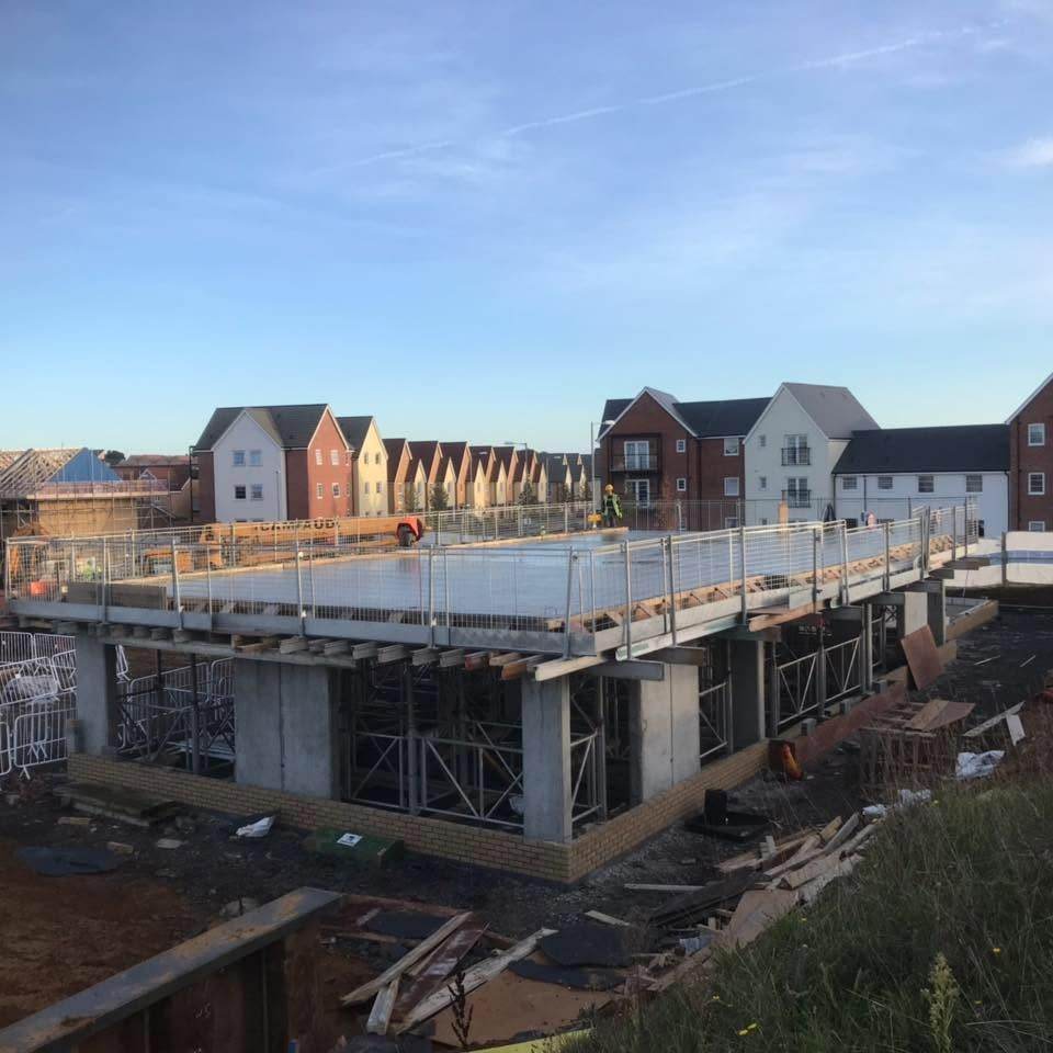 Reinforced concrete podium deck under construction with houses in the background