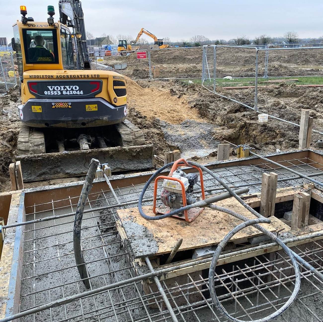Excavator positioned beside a reinforced concrete base